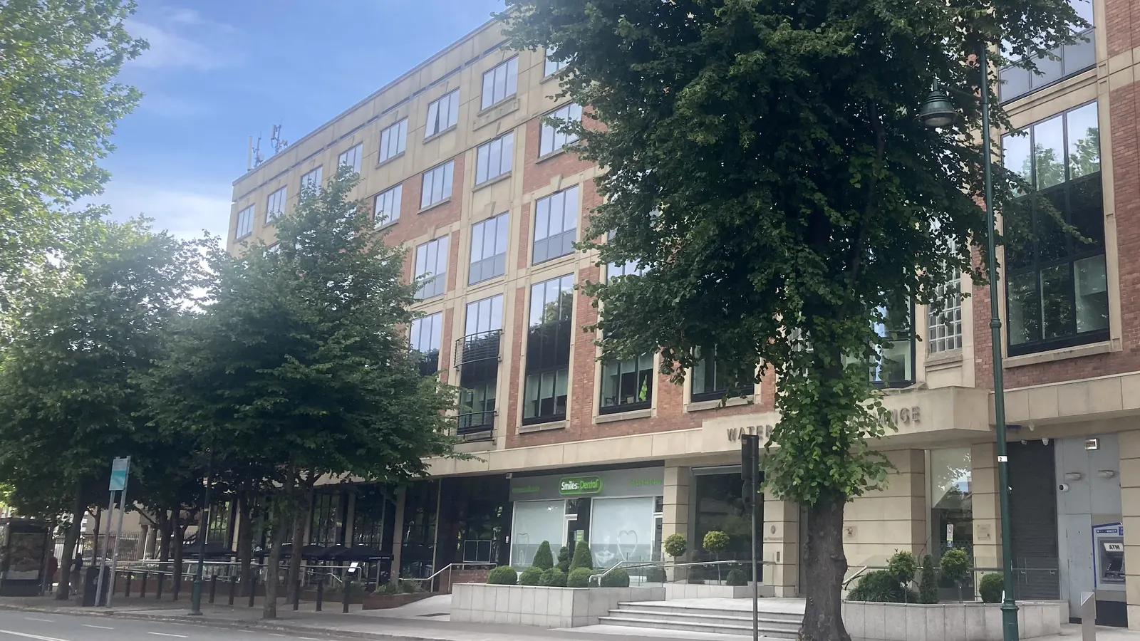 Edificio de oficinas Waterloo Exchange en Waterloo Road, Dublín, sede de Jazz Pharmaceuticals: fachada de ladrillo rojo y piedra clara con grandes ventanales y árboles en la acera, bajo un cielo azul.
